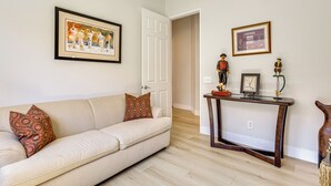 A living room with a sofa, a coffee table, and a door leading to another room. - Indian Palms Retreat Across From Empire Polo Club (Indio)
