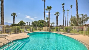 A clear blue swimming pool surrounded by a white fence, with palm trees and a clear sky in the background. - Indian Palms Retreat Across From Empire Polo Club (Indio)