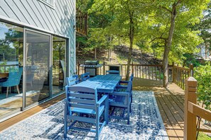 A deck with a table and chairs, a grill, and a glass door leading to a room. - Boat Dock & Slip! Group-ready Lake Ozark Home (Lake Ozark)