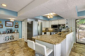 A kitchen with a central island, white cabinets, and a view of the outdoors. - Boat Dock & Slip! Group-ready Lake Ozark Home (Lake Ozark)