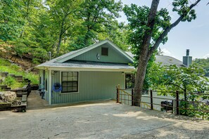 A small, single-story building with a sloped roof, a porch with a bench, and a wooden fence. - Boat Dock & Slip! Group-ready Lake Ozark Home (Lake Ozark)