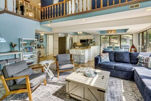 A spacious living room with a high ceiling, a kitchen area, and a view of the outdoors through large windows. - Boat Dock & Slip! Group-ready Lake Ozark Home (Lake Ozark)