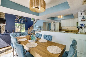 A dining area with a wooden table, blue upholstered chairs, and woven placemats. - Boat Dock & Slip! Group-ready Lake Ozark Home (Lake Ozark)
