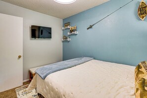 A bedroom with a bed, a television on the wall, and a shelf with various items. - Boat Dock & Slip! Group-ready Lake Ozark Home (Lake Ozark)