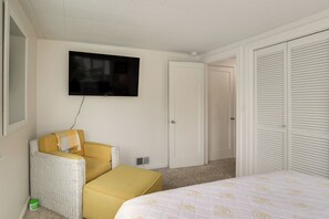 Quarto de hotel com cama, sofá, televisão e armário.