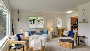 A cozy living room with wicker furniture, a sofa set, a dining area, and a kitchen visible through an open door. - Walk to Beaches! Lincoln City Family Home w/ Yard (Lincoln City)
