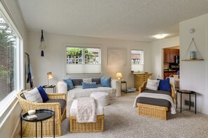 A cozy living room with wicker furniture, a sofa set, a dining area, and a kitchen visible through an open door. - Walk to Beaches! Lincoln City Family Home w/ Yard (Lincoln City)