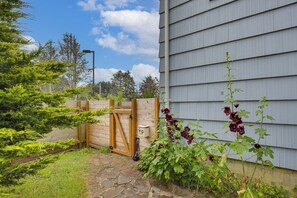A residential property with a wooden gate, a pet waste bin, and a variety of plants. - Walk to Beaches! Lincoln City Family Home w/ Yard (Lincoln City)