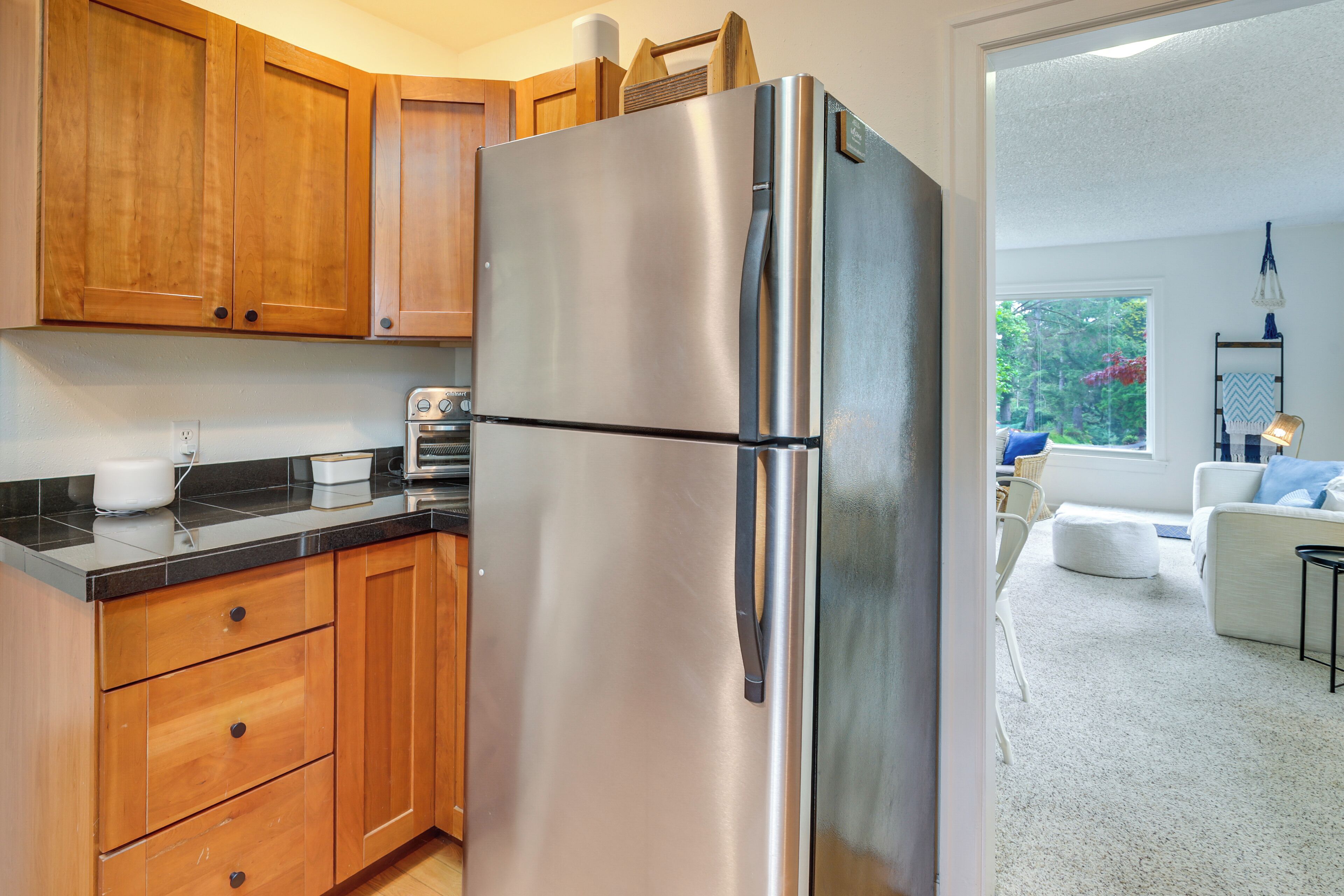 Una cocina con armarios de madera, un refrigerador de acero inoxidable y una tostadora sobre la encimera.