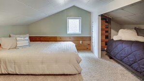 A bedroom with a sloped ceiling, a window, a wooden headboard, a bed with a white comforter, a purple comforter bed, and a small wooden dresser. - Walk to Beaches! Lincoln City Family Home w/ Yard (Lincoln City)
