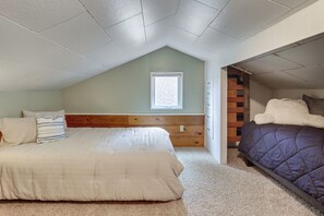 A bedroom with a sloped ceiling, a window, a wooden headboard, a bed with a white comforter, a purple comforter bed, and a small wooden dresser. - Walk to Beaches! Lincoln City Family Home w/ Yard (Lincoln City)