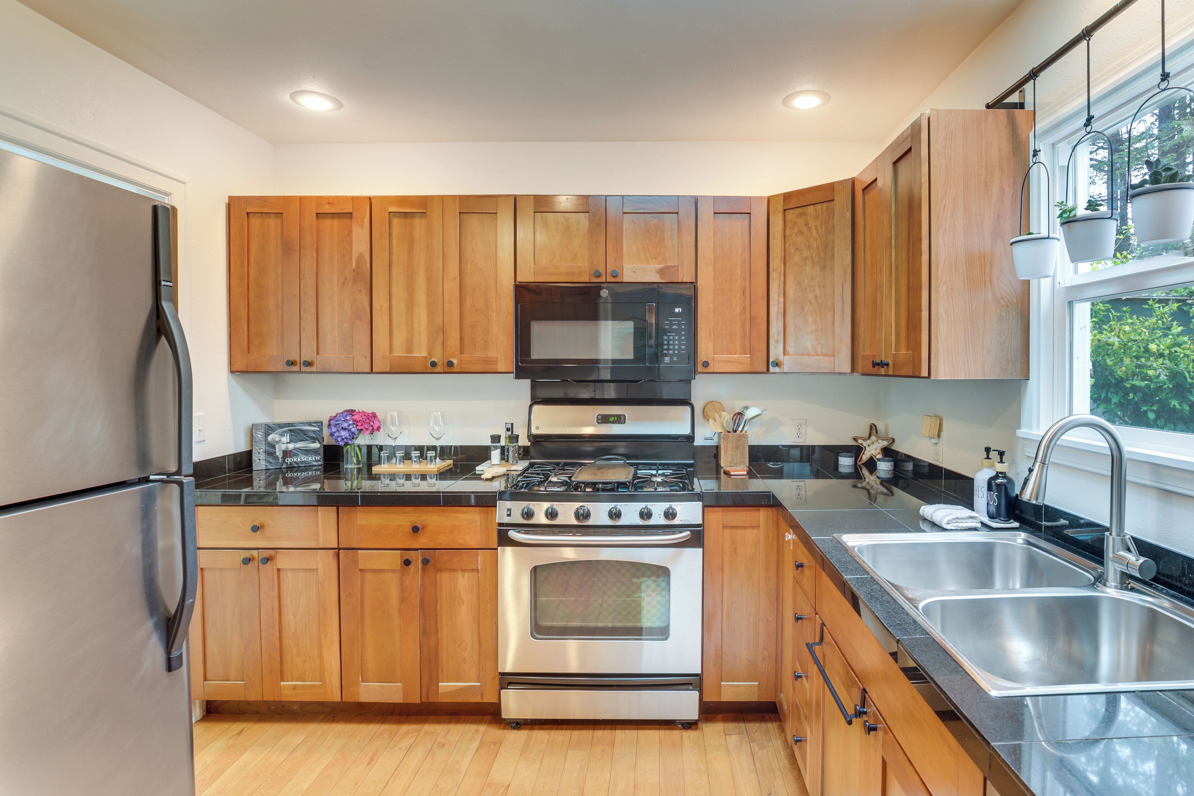 Una cocina moderna con armarios de madera, electrodomésticos de acero inoxidable y un ventanal que proporciona luz natural.