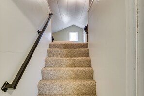 A carpeted staircase with a black handrail leading to a room with a window. - Walk to Beaches! Lincoln City Family Home w/ Yard (Lincoln City)