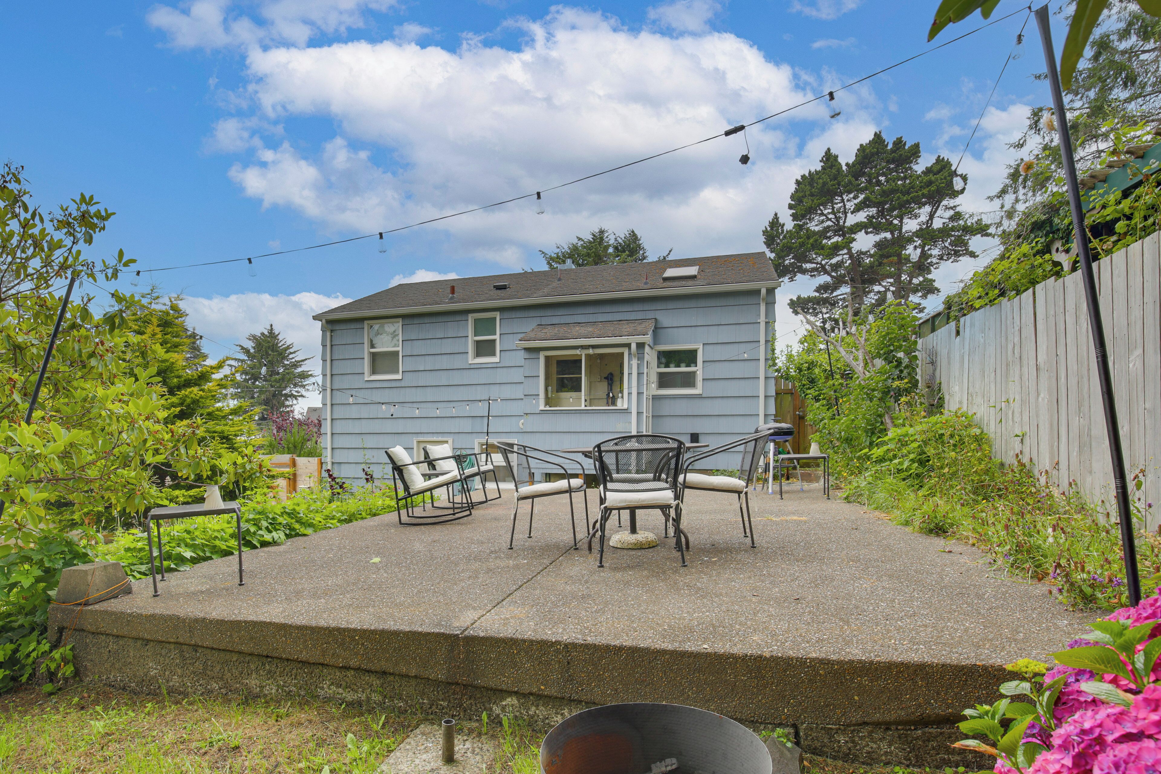 Ein Garten mit Terrasse, Gartenmöbeln und einem Haus.