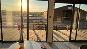 A room with a large window overlooking a wooden deck and a barn. - Equi Lodge Mer: A Horse-Loving Retreat Near Disney (La Houssaye-en-Brie)
