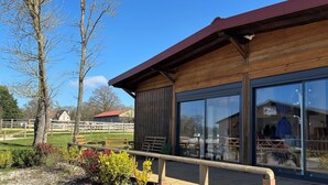 A wooden building with large windows, a wooden deck, and a gravel path. - Equi Lodge Mer: A Horse-Loving Retreat Near Disney (La Houssaye-en-Brie)