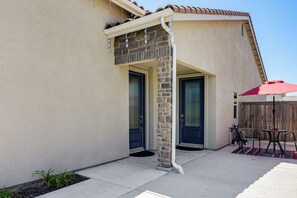 A house with a covered patio area, two doors, and a small outdoor seating area with a table and chairs.