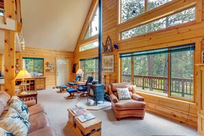 A cozy cabin interior with a fireplace, leather furniture, and large windows offering a view of the surrounding forest. - Durango Mountain Escape: Hike, Bike & Explore! (Durango)