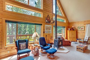 A cozy cabin interior with wooden walls, large windows, a fireplace, and a variety of seating options. - Durango Mountain Escape: Hike, Bike & Explore! (Durango)