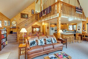 A spacious living room with a brown leather sofa, a dining area, a kitchen, and a staircase leading to an upper level. - Durango Mountain Escape: Hike, Bike & Explore! (Durango)