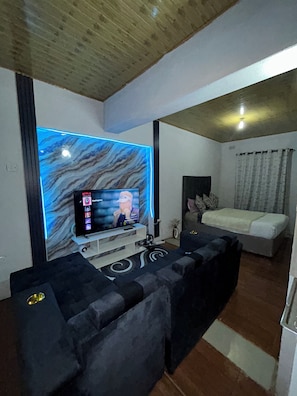 A modern living room with a flat-screen TV, a sofa, and a patterned wall.