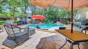 Ein Garten mit Schwimmbad, Gartenmöbeln und Grill.