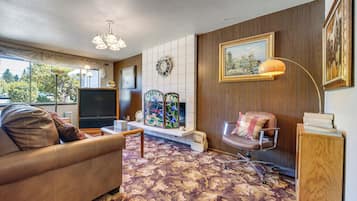 A living room with a sofa, a TV, a fireplace, and a painting on the wall.