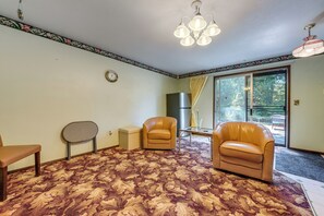 A room with a patterned carpet, two leather chairs, a small table, a clock on the wall, and a ceiling light fixture. - Private Yard & Patio! Pet-friendly Lynnwood Home (Lynnwood)