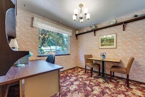A room with a wooden desk, a chair, a table with two chairs, a window with a view of greenery, a chandelier, and a framed picture on the wall. - Private Yard & Patio! Pet-friendly Lynnwood Home (Lynnwood)