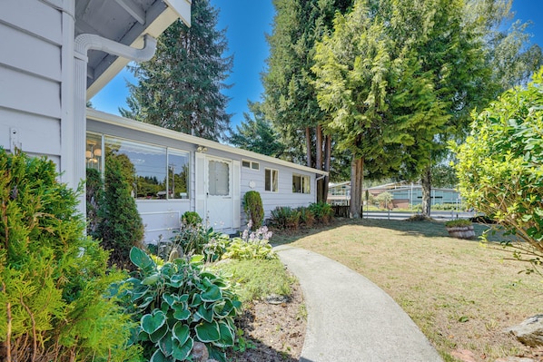 A single-story house with a covered porch, surrounded by lush greenery and a clear sky. - Private Yard & Patio! Pet-friendly Lynnwood Home (Lynnwood)