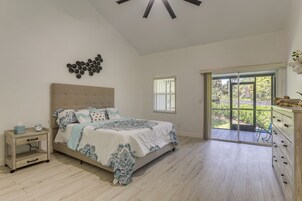 Une chambre à coucher comprenant un lit, une table de chevet et une vue sur l’extérieur grâce à une porte coulissante.