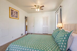 A bedroom with a bed, a ceiling fan, a door, and a window with curtains. - Near Riverwalk & Lake Adventures! Pueblo Home (Pueblo)