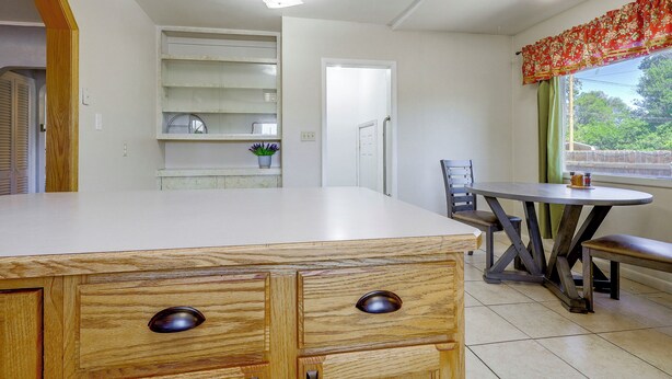 A kitchen with a wooden counter, a dining table with chairs, and a window with a view of greenery. - Near Riverwalk & Lake Adventures! Pueblo Home (Pueblo)