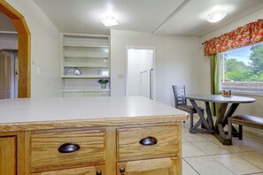 Une cuisine avec un comptoir en bois, une table à manger avec des chaises et une fenêtre donnant sur un paysage verdoyant.