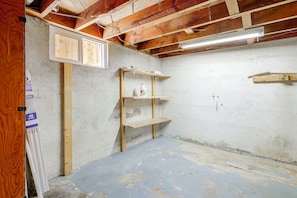 Ein Zimmer mit freiliegenden Holzbalken, einem Betonboden und einem Regalelement mit Reinigungsmitteln.