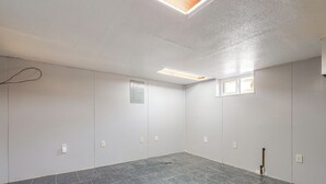 A room with a tiled floor, white walls, a ceiling light, a window, and electrical outlets. - Near Riverwalk & Lake Adventures! Pueblo Home (Pueblo)