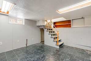 Une pièce dotée d’un sol en marbre noir, d’un escalier en bois et d’une fenêtre avec des stores.