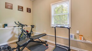 A home gym with exercise equipment, a window with blinds, and motivational wall art. - Family Getaway in Kennesaw! Spacious Home (Kennesaw)