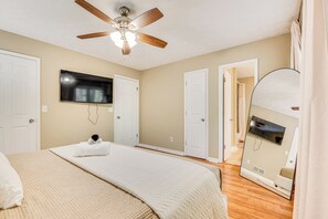 A bedroom with a bed, a ceiling fan, a flat-screen TV, and a large mirror. - Family Getaway in Kennesaw! Spacious Home (Kennesaw)