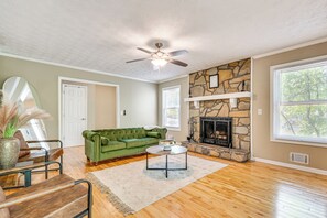 A living room with a green sofa, a coffee table, a fireplace, and a ceiling fan. - Family Getaway in Kennesaw! Spacious Home (Kennesaw)