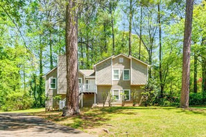 A two-story house with a front porch and a garage, surrounded by trees. - Family Getaway in Kennesaw! Spacious Home (Kennesaw)