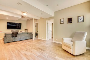 A modern living room with a grey sofa, a white armchair, and a flat-screen TV mounted on the wall. - Family Getaway in Kennesaw! Spacious Home (Kennesaw)