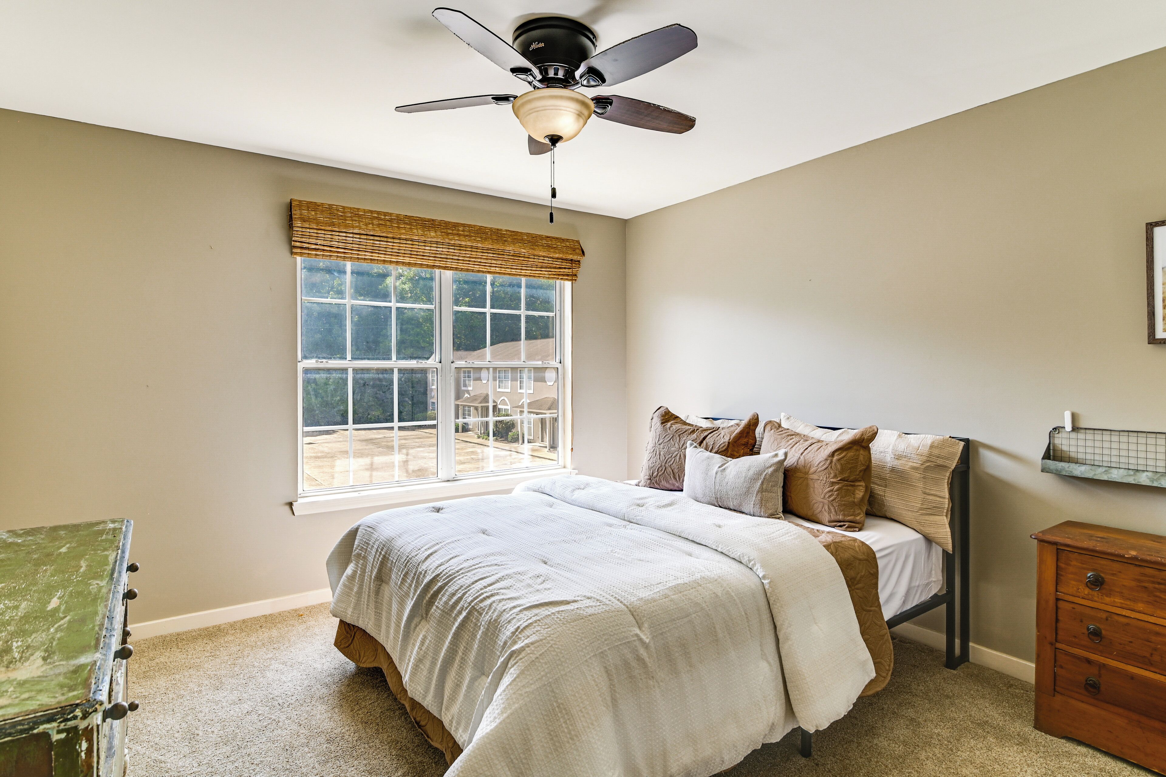 A bedroom with a bed, a window, a ceiling fan, and a dresser.