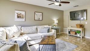 Ein Wohnzimmer mit einer Couch, einem Couchtisch, einem Deckenventilator und Kunstwerken an der Wand.