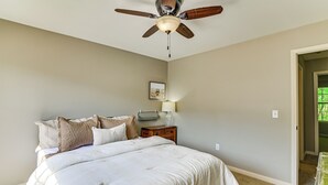 Ein Schlafzimmer mit einem Bett, einem Nachttisch, einem Deckenventilator und einer Tür zu einem anderen Raum.
