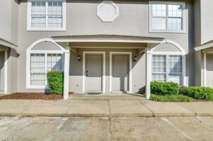 A two-story building with a covered entrance, a front door, and a small porch area.