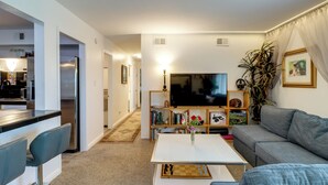 A modern living room with a sofa, a coffee table, a TV, and a bookshelf. - Walkable & Renovated Gem! Only 8 Mi to Dtwn Tucson (Tucson)