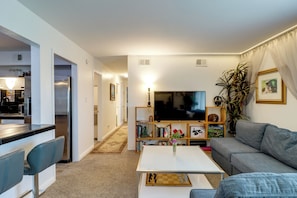 Ein modernes Wohnzimmer mit einer Couch, einem Couchtisch, einem Fernseher und einem Bücherregal.