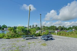 Une zone recouverte de gravier avec des tables de pique-nique, une étendue d’eau et un quai pour bateaux en arrière-plan.