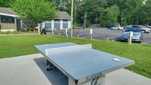 A table tennis table outdoors with a building and parked cars in the background. - Lewes Family Escape w/ Angola by the Bay Amenities (Lewes)